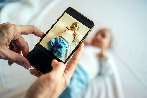 Mother taking photo of a baby with smartphone.