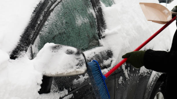 istock Scraping the snow of a car using the brush. 1182830594