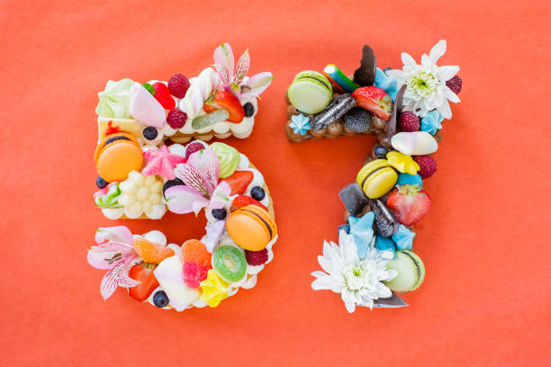 Abundantly decorated cake with jelly beans, macaroons, fruit and flowers in shape of number 57