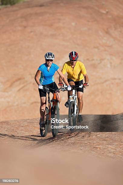 Photo libre de droit de Jeune Couple Riding Mountain Bikes Sur Les Dunes De Sable Pétrifiée banque d'images et plus d'images libres de droit de Activité de loisirs