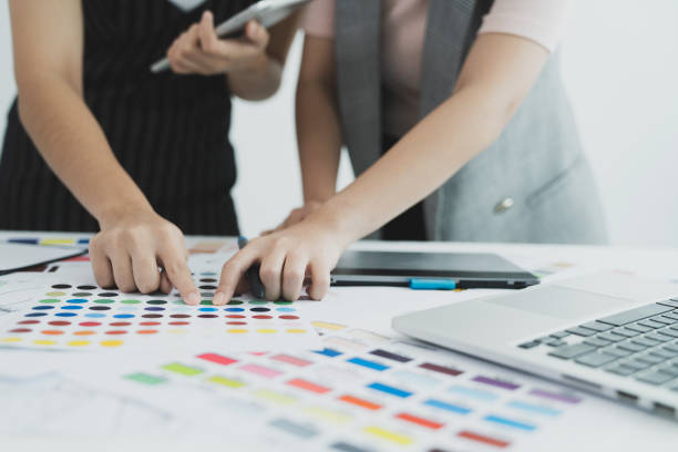 istock Graphic designer at work. Color swatch samples. Team designer working graphic with color chart and meeting brainstorm for new project. Graphic designer drawing on graphics tablet at workplace. 1182833378
