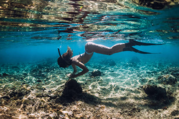 istock Slim young woman snorkeling over bottom with fish in underwater 1182838708