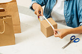 frau-verpackt-kartons-mit-klebebandspend