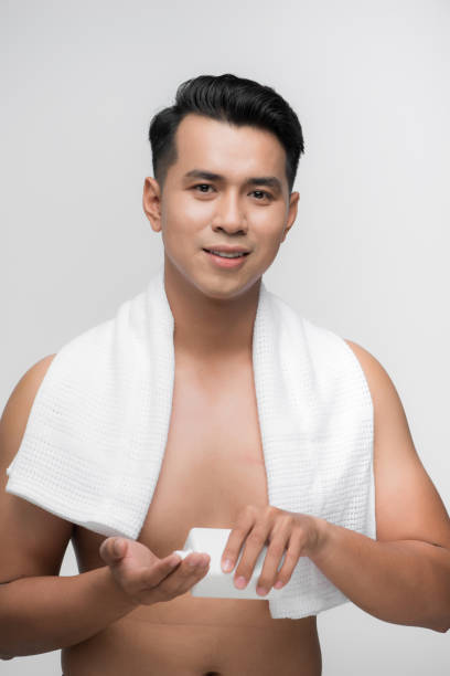 istock Attractive Vietnamese man applying moisturizer to face 1182843157