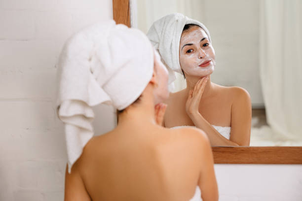 woman is applying mask on her face - face mask imagens e fotografias de stock