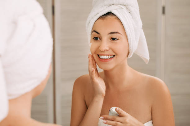 istock woman applying cream on her face in bathroom 1182843955