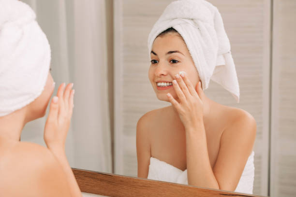 istock woman applying cream on her face in bathroom 1182844701