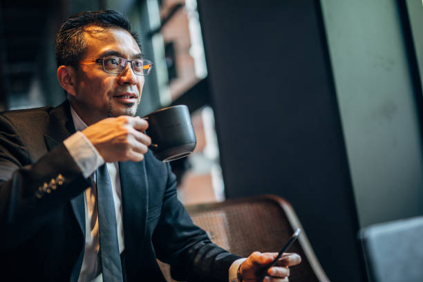 istock Chinese businessman drinking coffee in cafe 1182845536