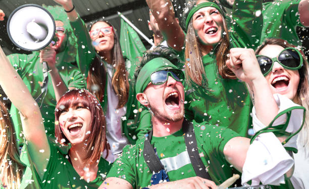 junge amateur-fußball-fan-fans jubeln mit konfetti beobachten lokalen fußball-cup-spiel im stadion - freunde gruppe auf grünen t-shirts mit aufgeregt spaß auf sport-wm-finale - rugby shirt stock-fotos und bilder