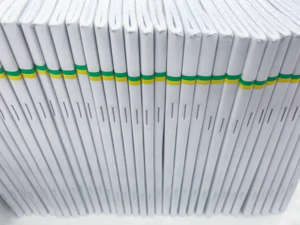Top view of a pile of notebooks in a cage with a white cover and stripes of yellow and green
