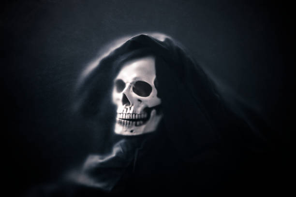 istock Grim reaper in the dark behind a dusty scratched glass. 1182848531