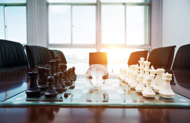 istock Chess pieces and glass earth globe on the conference table 1182848836