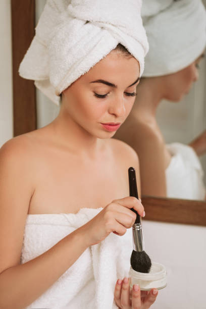 istock woman applying makeup on face at home 1182850754