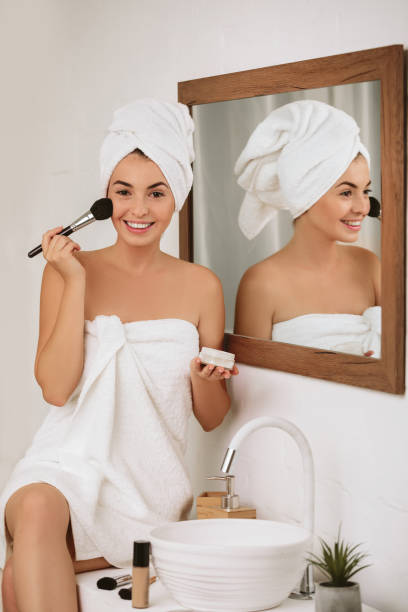 istock woman applying makeup on face at home 1182850810