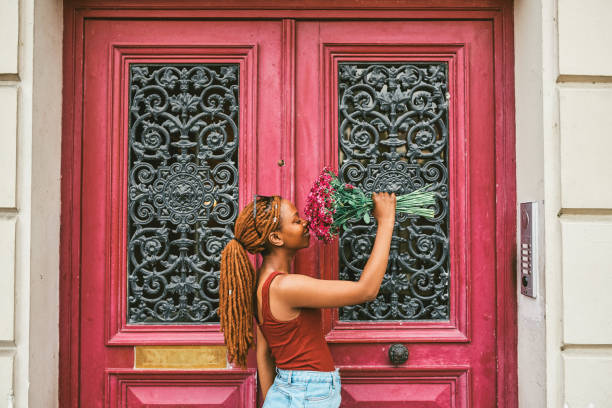 Shot of an attractive young woman smelling her bouquet of flowers in front of a doorway in Paris, France