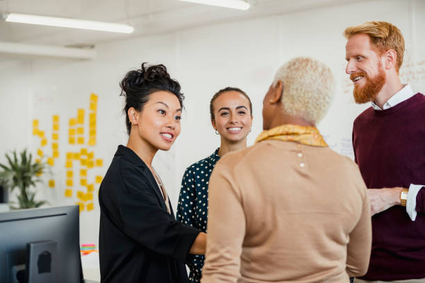 Brainstorming as a Group Colleagues standing in a small group discussing something while working at an office. ethnic diversity stock pictures, royalty-free photos & images