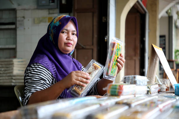 Portrait of Muslim Woman - Malaysia A female adult is feeling cheerful at her business stall selling famous 'kueh lapis' (traditional local colourful layer cake). small business malaysia stock pictures, royalty-free photos & images