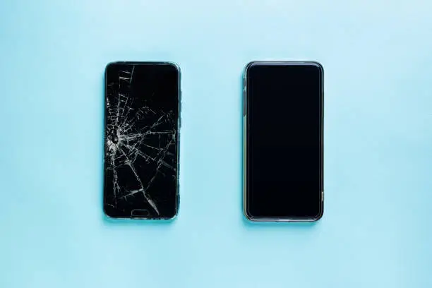 Modern touch screen smartphone with broken screen and new one on blue background, top view