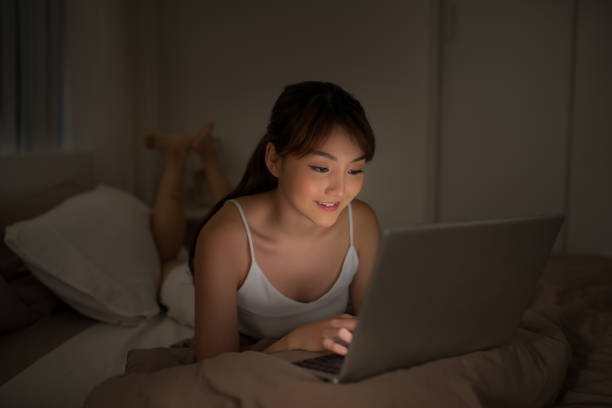 istock Bedroom evening - woman with laptop lying down in bed 1182858413