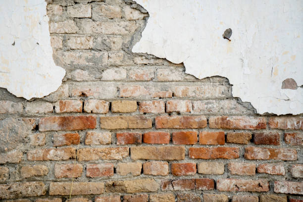 istock Old brick wall with damaged white plaster 1182858941