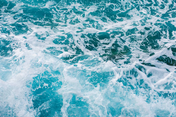 istock Turquoise sea surface background with splashing waves 1182860388