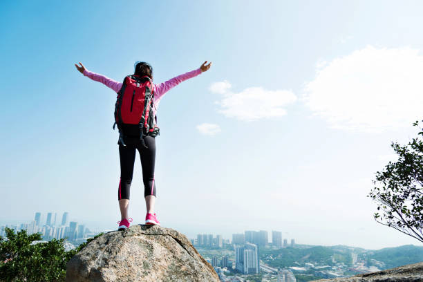 Woman backpacker standing on the mountain peak rock.