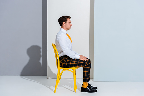 side view of man in checkered trousers sitting on white and grey