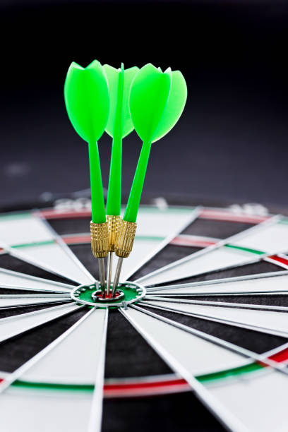 hitting the bulls eye on the black background - bulls eye dart target dartboard imagens e fotografias de stock