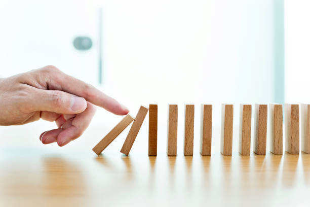 istock Man hand pushing domino pieces 1182865303