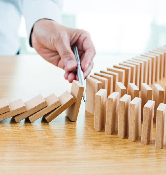 istock Businessman hand holding a pen stop domino effect 1182865335