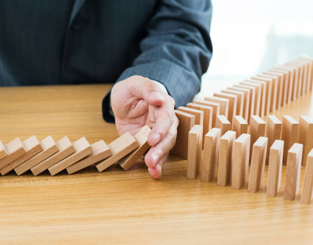 istock Businessman hand stopping falling blocks on table 1182865357