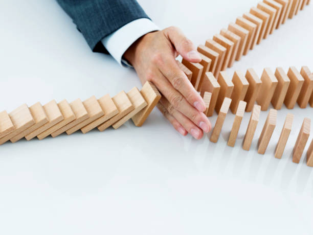 istock Businessman hand stopping falling blocks on table 1182865418