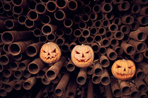 calabazas de halloween en una pila de tuberías oxidadas - halloween pumpkin jack olantern industry fotografías e imágenes de stock