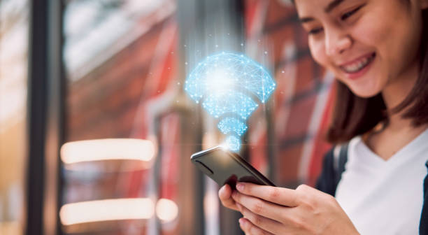 istock Wireless and connection network technology concept, smiling Asian woman using smartphone show wifi icon at the mall. 1182866792