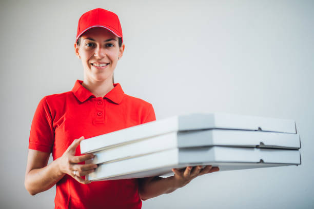 Young cute caucasian pizza delivery woman holding pizza boxes.