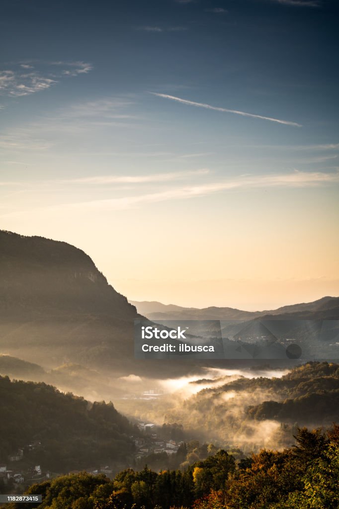 Névoa da manhã do nascer do sol na vila pequena nos Alpes italianos, Piedmont, monte Fenera - Foto de stock de Piemonte royalty-free