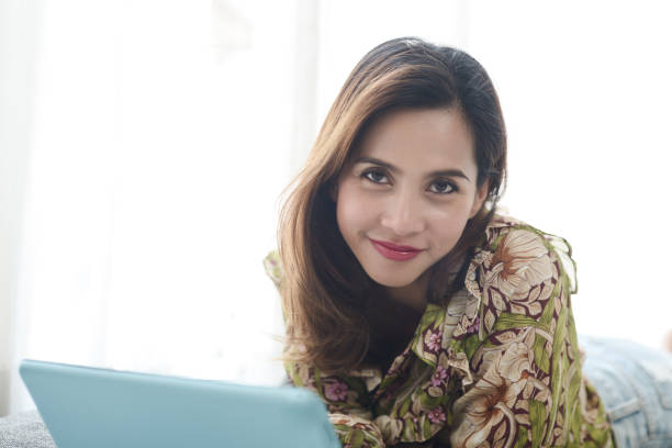 istock Happy Asian woman laying down on floor and using tablet. 1182874633