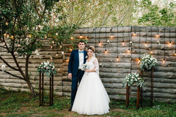 istock Wedding couple in magical evening forest decorated light garlands. Ceremony with lanterns and lamps decorated flowers. Bride and groom on background of bulb lights. 1182874749