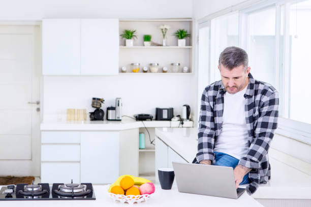 istock Caucasian man using a laptop in the kitchen 1182877746