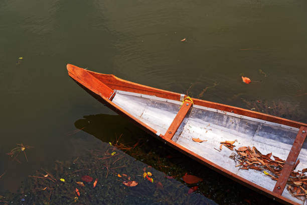 Wooden boats lie side by side, tied by rope to a nearby peg in Fredrikstad, Norway.