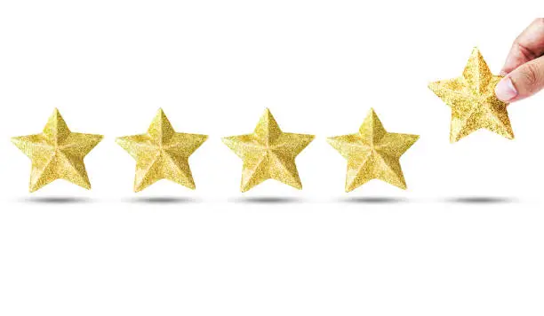 Photo of Isolated Hand putting luxury golden star for increase star unit from 4 pieces to 5 pieces on white background. Excellent business service rating concept.