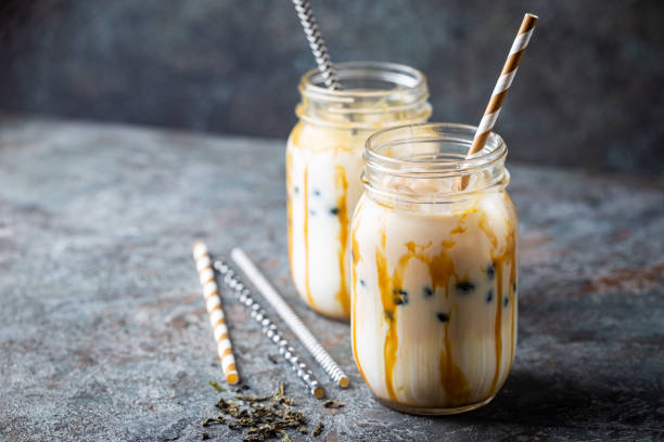Creamy bubble tea Light brown creamy bubble tea with milk and black tapioca in a glass jar on gray background bubble tea photos stock pictures, royalty-free photos & images
