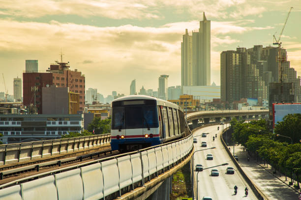 skytrain работает на железной дороге по улице со зданиями и капризный фон неба. - mass transportation стоковые фото и изображения