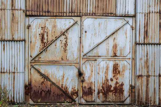 Closed old rusty iron gate sash in a corrugated iron wall. Abandoned industrial building. Grunge