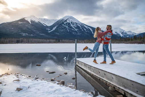 Two people relaxing in winter by the lake contemplating nature together