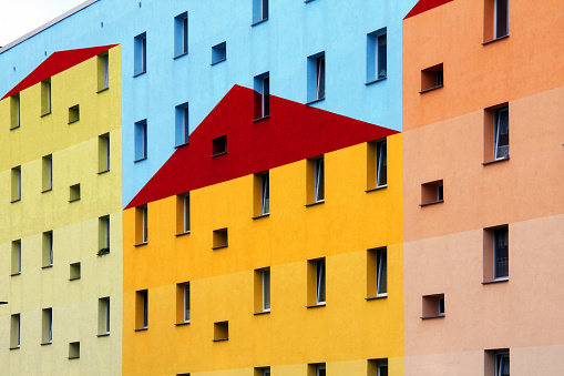Distinctive facade of a colorful modern building with different shapes and colors and with windows. 