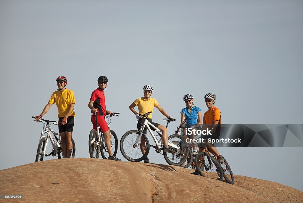 Group Of Mountain Bikers On Slickrock Trail In Moab, Utah Group of five cyclists on top of huge mound on Slickrock Trail smiling and looking at the camera. Cycling Stock Photo