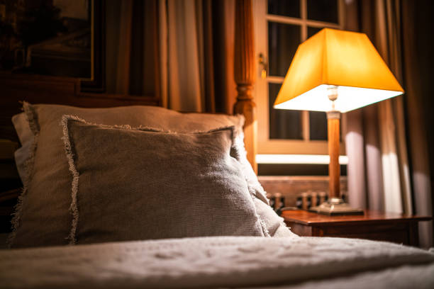 istock Lamp on a night table next to a bed 1182901685