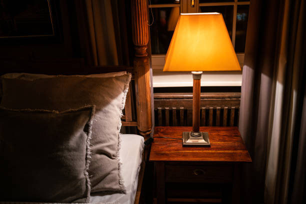 istock Lamp on a night table next to a bed 1182901702