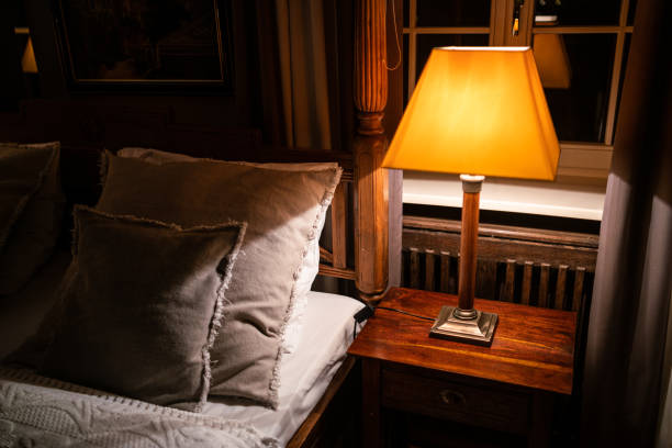istock Lamp on a night table next to a bed 1182901754
